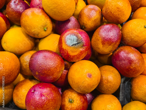 Fruits gathered in a market during daytime with a variety of colors and some showing signs of spoilage