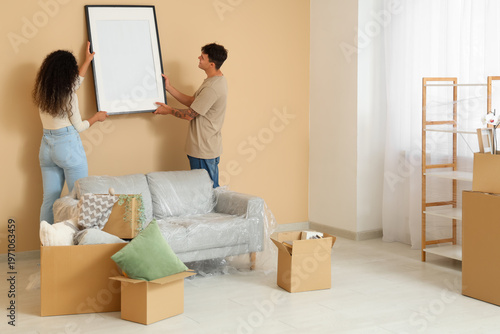 Young couple hanging pictur...