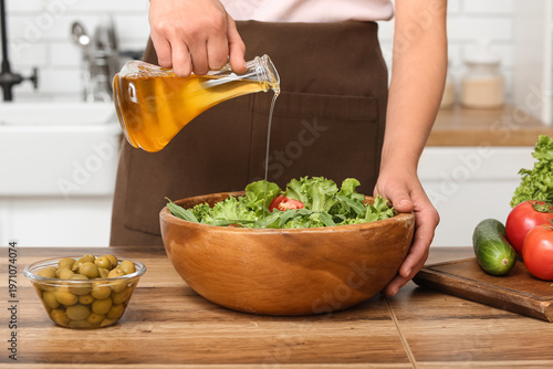 Woman adding olive oil into...