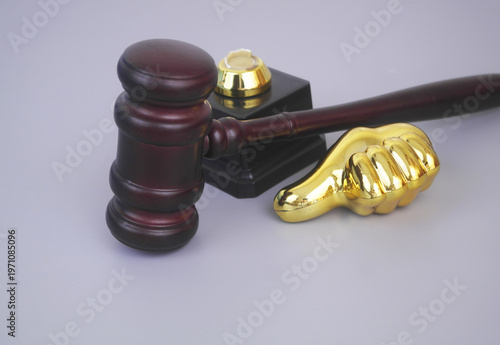 Broken golden thumbs up and wooden judge gavel on grey background. Bad legal service and court concept.