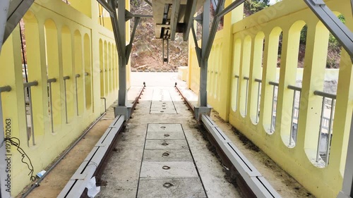 Mechanical hoist for water control stands firmly on top of a massive dam. A large steel gantry crane sits on metal rails. This functional mechanical hoist manages water control at the facility.