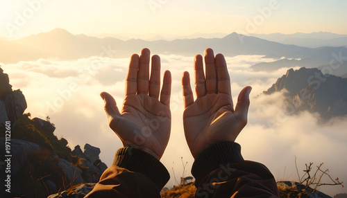 Two hands outstretched toward golden sunlight overlooking a mountain range above clouds