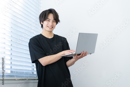 窓際でパソコンを見る若い男性