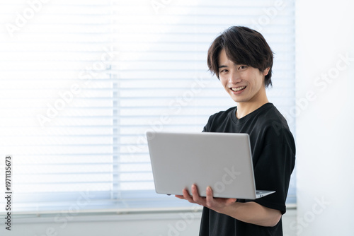 窓際でパソコンを見る若い男性