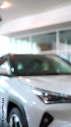 Close-up of car dealer handing over a key to a customer in a showroom. Successful vehicle purchase and ownership transfer. Automotive sales concept. Vertical Shot