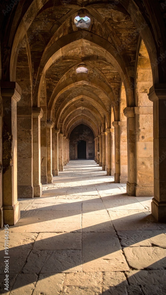 Obraz premium Perspective view of arched hallway with stone columns and sunlight creating a spiritual and architectural exploration