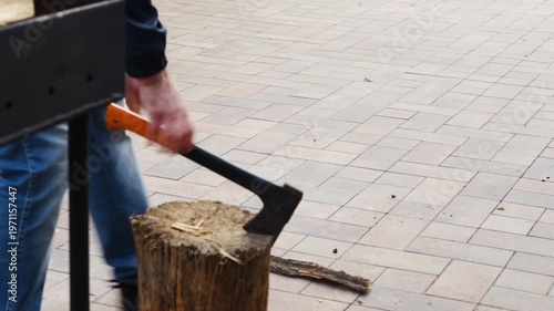 Chopping wood outdoors in a backyard setting on a sunny day with clear sky and simple tools for firewood preparation