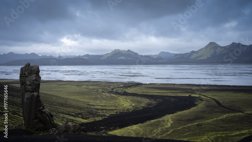 Rough volcanic landscape with mountains, glacial rivers and heavy clouds above, Iceland