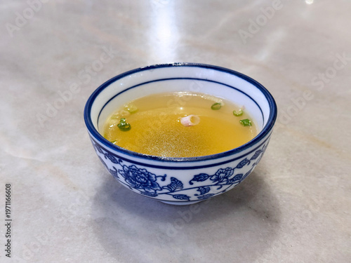 double boiled hot healthy chicken clear soup with spring onion in ceramic chinese classic bowl on white marble table dim sum halal food breakfast menu for china Hong Kong cafe