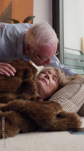 Senior man caring for sleeping woman on couch