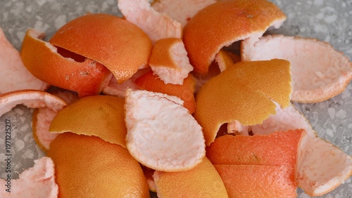 Close-up shot of a pile of fresh grapefruit peels on a grey kitchen surface.