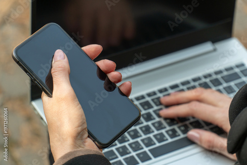 Woman holding smartphone near laptop for secure digital banking payment mockup