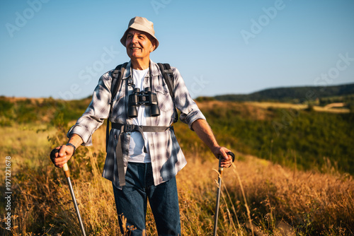 Portrait of active senior hiker smiling while enjoying hiking in nature.