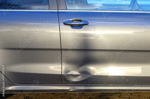 Fotografija Close-up of a dented car door with scratches and reflections