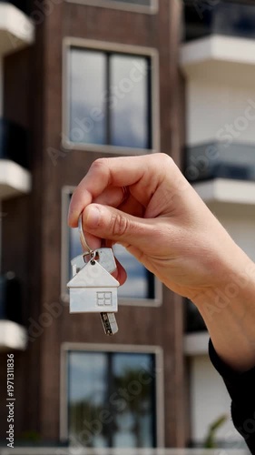 Key to new home with house-shaped keychain, symbol of property purchase and homeownership.