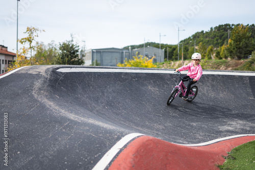 A young girl riding a bike on a skate park ramp on a sunny day