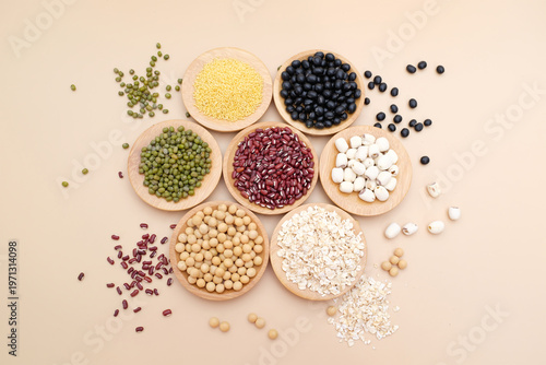 Top view close-up of various whole grains and legumes arranged in wooden bowls on a neutral background