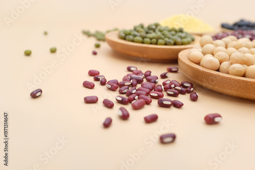Various types of beans displayed in wooden bowls with scattered grains on a light background