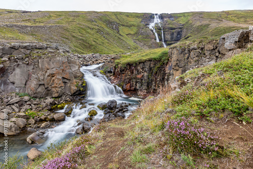 Waterfall winds through the valley across Eastern Iceland in the summer