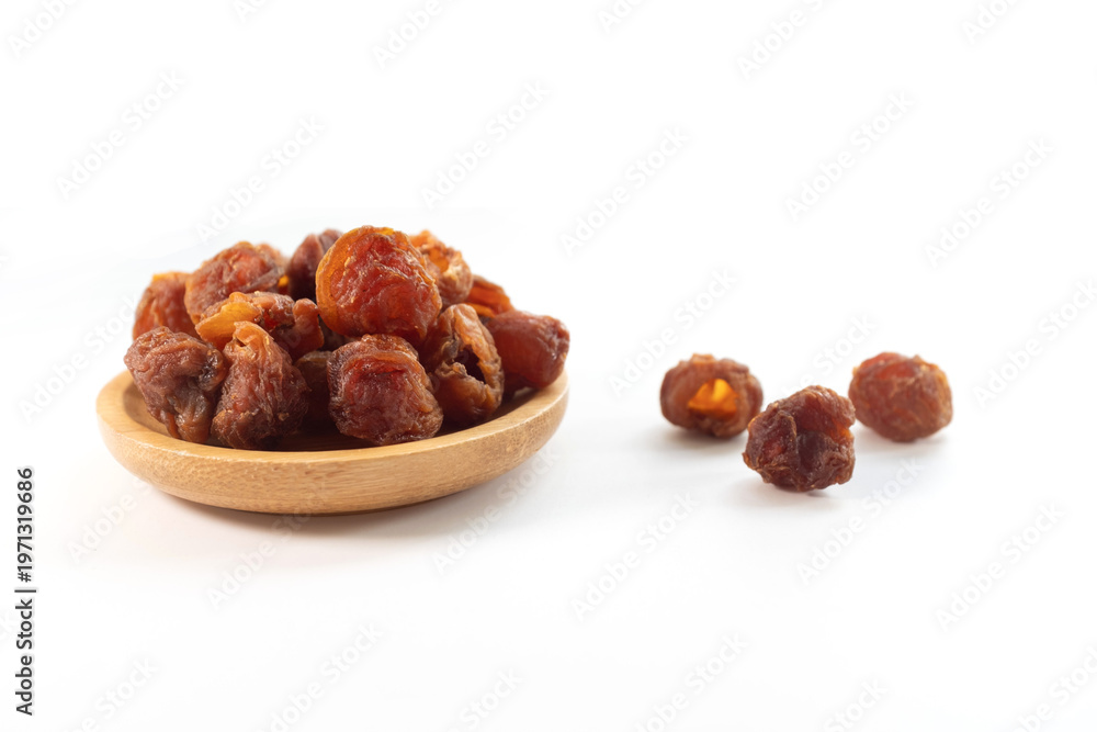 Obraz premium Dried longan fruits in a wooden bowl captured in close-up still life photography