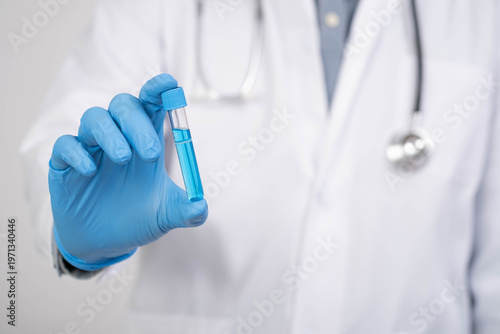 Doctor holding laboratory test tube with blue liquid sample, representing medical research, vaccine development, laboratory testing, pharmaceutical science and healthcare innovation.