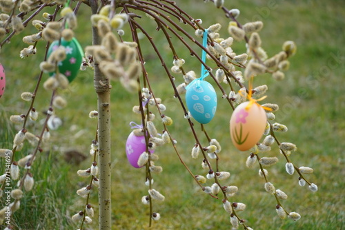 colorful eggs hang from palm branches.