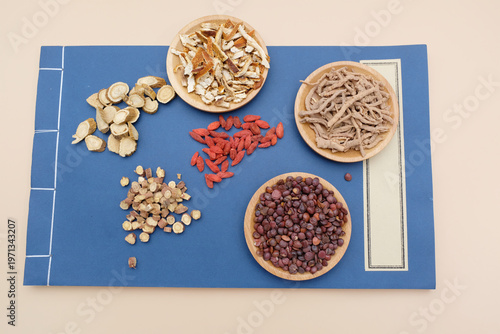 Various traditional Chinese medicinal herbs arranged in wooden bowls on a blue background