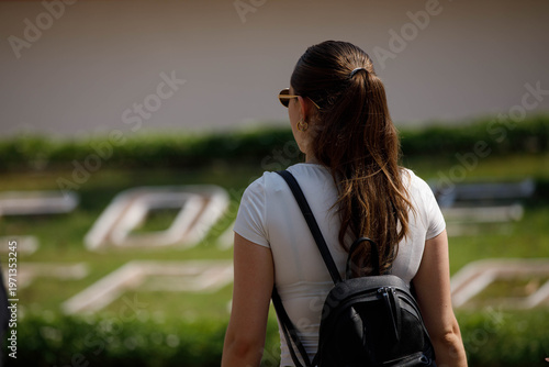 Female backpacker walking touring, walking motion, step movement, pedestrian stride, person in natural sunlight, rear view, at Maharat Road.