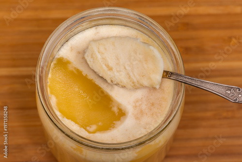 Crystallized white honey in glass jar and in spoon atop