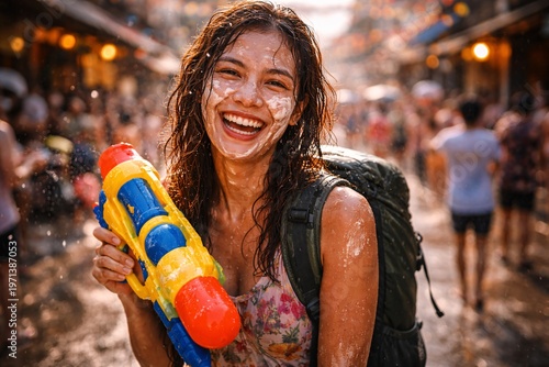 Soaking wet woman laughing with water gun at Songkran festival