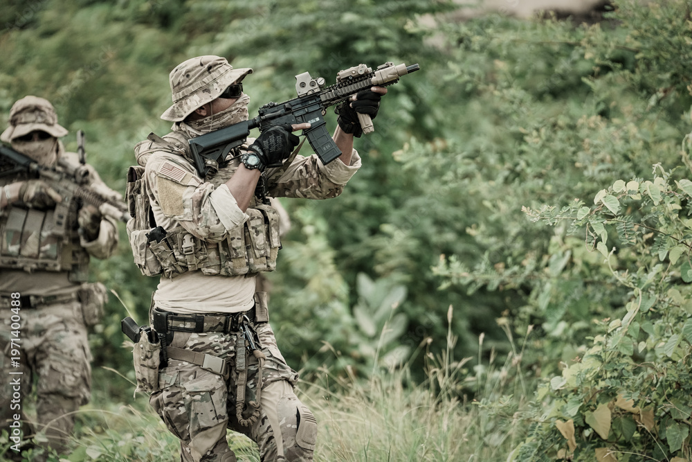 Obraz premium Two soldiers in camouflage gear aiming rifles in a dense green forest environment