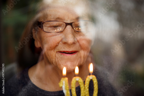 Bild auf Leinwand Portrait of an elderly woman with glasses holding anniversary candles