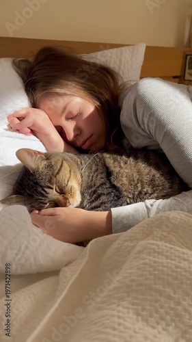 This captures a heartwarming moment of a woman sleeping peacefully in bed with her cat. The scene exudes a sense of calmness and serenity, showcasing a tender moment between a pet and her owner in a