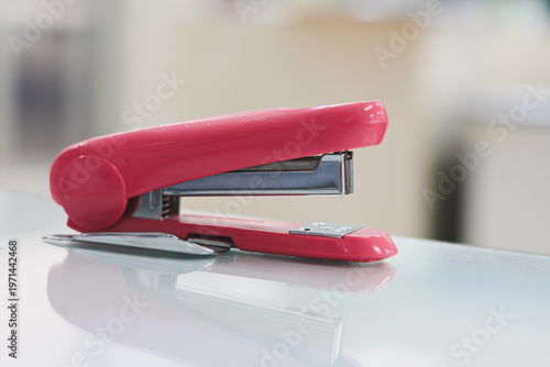 A bright pink stapler resting on a smooth surface.