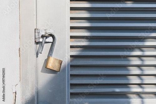 An open padlock hanging on a metal door hinge.