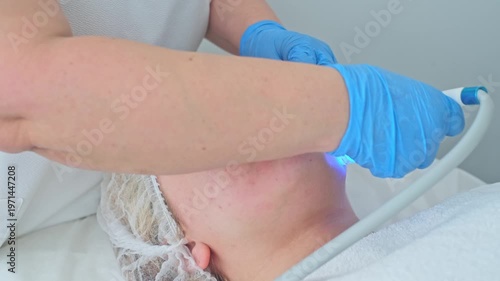 Cosmetologist performs an advanced hydro-peeling treatment using blue light for deep cleansing and rejuvenation on a client.