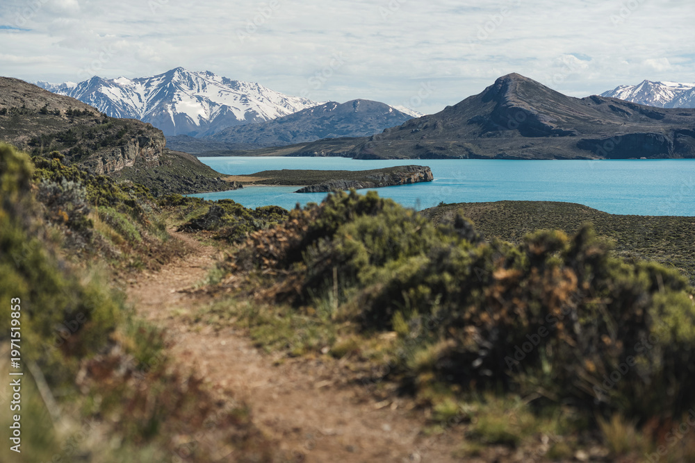 Obraz premium Hiking trail overlooking turquoise lake and snowy mountains