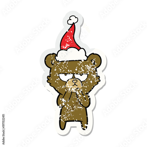 Distressed sticker of a grumpy cartoon bear wearing a festive red santa hat