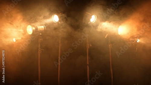 Canvastavla Multiple professional stage spotlights on stands shine in a dark smoke studio with visible beams