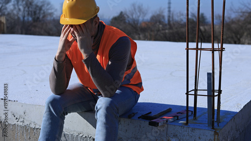 Construction worker having a depressed period, headache, issues on a construction site outdoors.