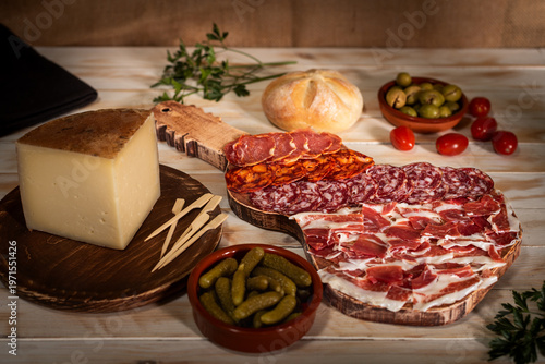 Fotografie Boards with cured meats, ham and cheese, accompanied by olives, pickles and bread, gastronomic still life