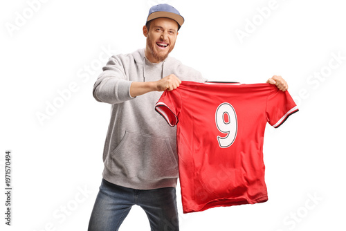 Man in a hoodie and a cap holding a red sports jersey and cheering