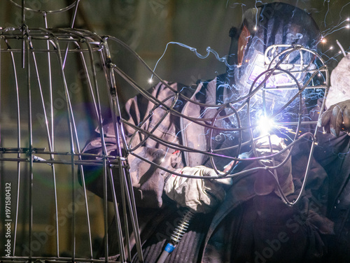 Photos Close-up of a professional metalworker in a protective welding mask and heavy-du