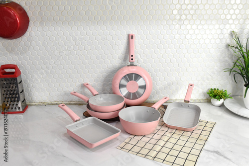 Photos Kitchen cookware styling with pink pots and pans and plants.