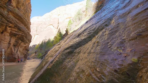 Low angle shot of the Virgin River flowing through the towering sandstone walls of The Narrows in Zion National Park, Utah