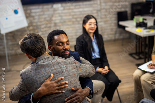 Foto Two colleagues sharing a supportive hug during a group therapy session in the office