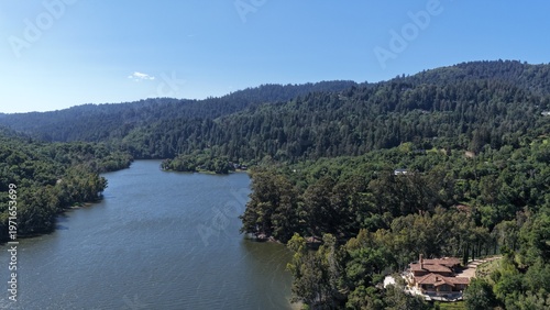 Aerial view of Lexington Reservoir surrounded by lush green hills and forest in Los Gatos, California