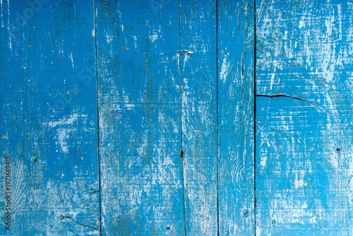 Close-up of weathered blue painted wooden planks with peeling layers, cracks and aged texture. Rustic surface ideal for vintage backgrounds and design use.