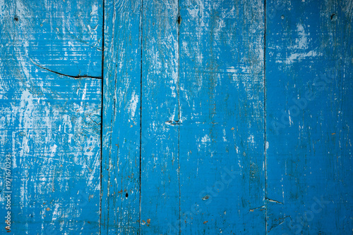Close-up of weathered blue painted wooden planks with peeling layers, cracks and aged texture. Rustic surface ideal for vintage backgrounds and design use.