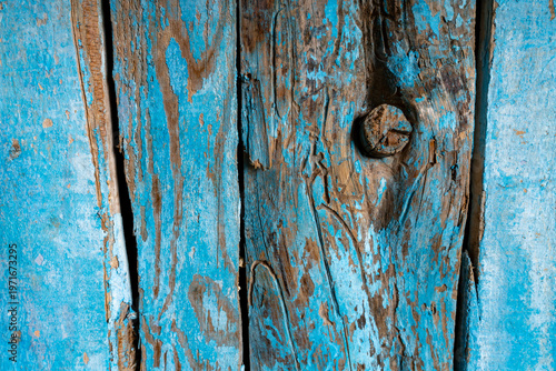 Close-up of weathered blue painted wooden planks with peeling layers, cracks and aged texture. Rustic surface ideal for vintage backgrounds and design use.